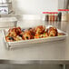 A Vollrath Wear-Ever aluminum roasting pan filled with meat and vegetables on a counter.