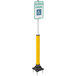 A yellow and white Impact Recovery Systems SlowStop steel bollard with a "Handicapped Reserved Parking" sign on it.