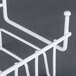 A white metal freestanding rack with hooks for Robot Coupe food processor discs.