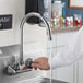 A person using a Regency gooseneck faucet to wash their hands.