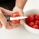 A person using a Mercer Culinary Millennia paring knife to cut a tomato.