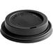 A black plastic Choice travel lid on a table for a hot beverage.