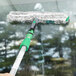 A hand using an Unger ErgoTec StripWasher mop to clean a wet window.