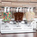 A close-up of a Zevro triple canister dry food dispenser filled with colorful cereal.
