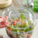 A person's hand using a clear Stalk Market lid on a plastic salad container.