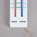 A Taylor white indoor/outdoor thermometer with blue and red text and a wire.