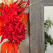 A hand holding a vase with red flowers and leaves reflected in a BrandtWorks Barnwood Gray Finish Mirror.