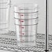 A wire rack of three Cambro clear plastic food storage containers.