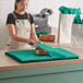 A woman in an apron cutting teal tissue paper on a table.