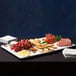 An American Metalcraft flat melamine platter with cheese, grapes, and crackers on a table.