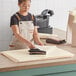 A woman in an apron cutting Lavex French vanilla tissue paper on a counter.