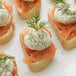 A group of small sandwiches with smoked salmon, cream cheese, and Regal Dill Weed sprigs.
