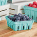 A green Pactiv half-pint molded fiber basket of blueberries.