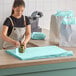 A woman wearing an apron cutting sky blue Lavex tissue paper on a counter.
