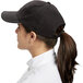 A woman wearing a black Chef Revival baseball cap with a ponytail.
