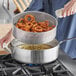 A person using a Vollrath Wear-Ever fry pot to cook onion rings in a professional kitchen.