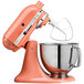 An orange KitchenAid Artisan mixer with a silver bowl.
