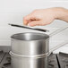 A person using a Vollrath stainless steel double boiler set on a stove.