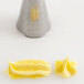 A yellow pastry bag with an Ateco open star tip filled with yellow frosting.
