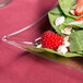 A clear Fineline plastic salad plate with a salad of strawberries, blueberries, and almonds.