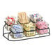 A black Cal-Mil 2-tier display with glass jars holding different colored condiments.