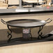An American Metalcraft wrought iron griddle on a matching stand on a counter.