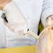 A person wearing white gloves using a Dexter-Russell V-Lo narrow boning knife to cut chicken.