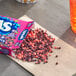 A box of Nerds candy on a table next to a glass of soda.