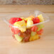 A Dart rectangular plastic container filled with fruit on a counter.