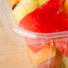A Dart clear rectangular plastic container filled with red and yellow fruit.
