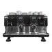 A black and silver Gaggia La Reale espresso machine on a counter with white cups on top.