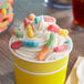 A cup of ice cream with Trolli Sour Brite gummy candy on top.
