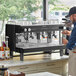 A man standing next to a Gaggia Vetro black espresso machine on a counter.