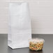 A Duro white paper bag with a handle next to a plastic container of pasta.