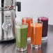 A Breville commercial juicer on a counter with glasses of juice.
