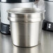 A Vollrath stainless steel inset pot with a lid on a counter.