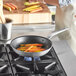 A Vollrath Wear-Ever aluminum non-stick fry pan with carrots cooking in it on a stove.