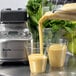 The Breville Commercial blender pouring a yellow smoothie into a container.
