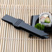 Fineline black plastic tongs serving a sushi roll on a black plate.