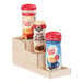 A Cal-Mil maple wood 3-step bottle display riser holding coffee creamer containers.