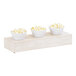 A row of three bowls of popcorn on a wood display riser.