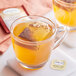 A glass mug of Twinings Orange & Cinnamon Spice tea with a tea bag in it.