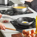 A woman cooking eggs in a Vigor SS3 stainless steel non-stick frying pan.