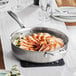 A Vigor stainless steel saute pan with chicken and vegetables.