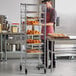 A man standing next to a Regency end load sheet pan rack filled with pastries.
