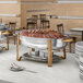 A white table with a Choice silver and gold chafing dish filled with meat on a large platter.