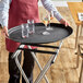 A person holding a black Carlisle non-skid serving tray with glasses of water and wine.
