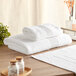A stack of white Lavex Luxury towels on a wooden table.
