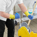 A person wearing blue and yellow Ansell AlphaTec gloves mopping a floor.