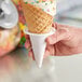 A hand holding an ice cream cone with a scoop of ice cream.